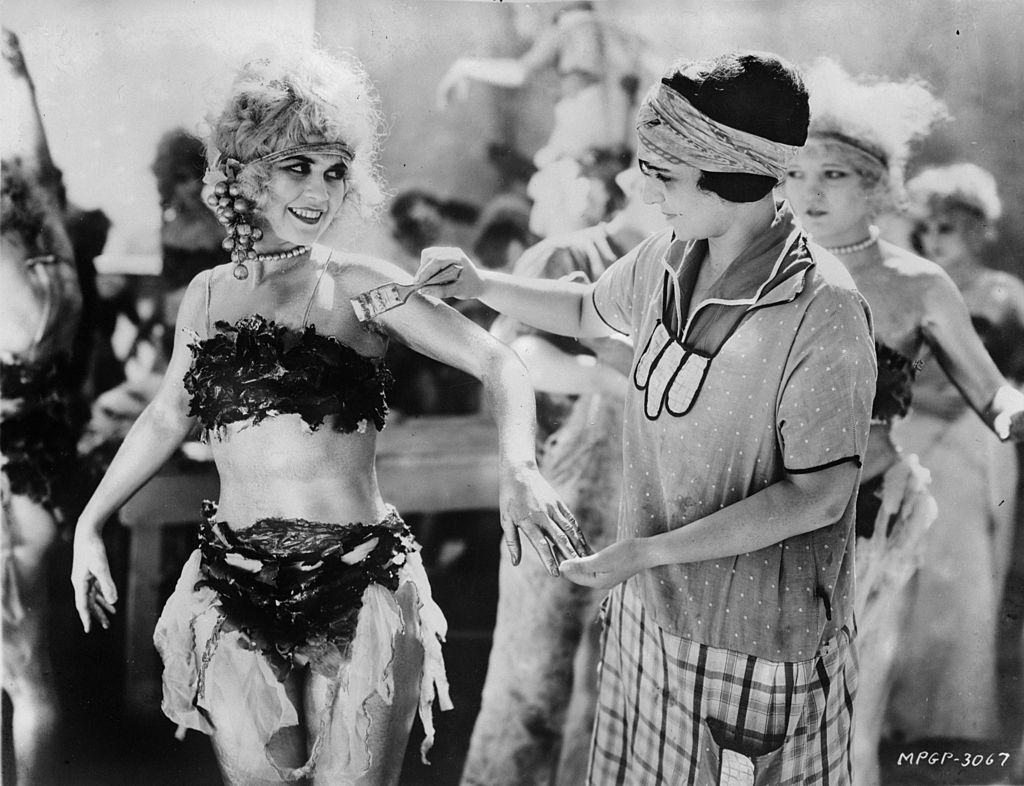 #13 Alice Terry has body paint applied by a make-up artist before filming commences, 1924.