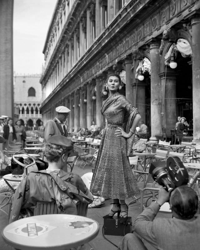 #20 Alla wearing a Christian Dior dress is being filmed at a cafe on the Piazza San Marco in Venice, 3rd June 1951