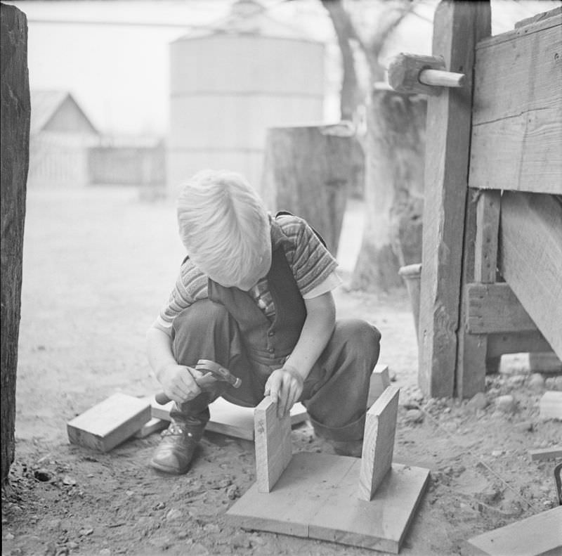 #3 Boy holding a small hammer, kneeling next to a couple wood planks