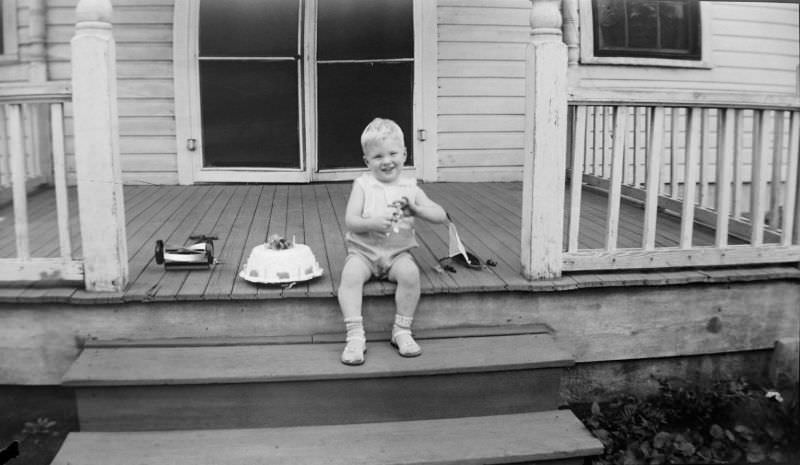#32 Smiling boy sitting on wooden steps and patio with various toys