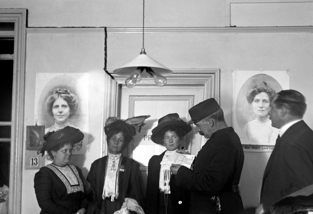 #32 Suffragettes Flora Drummond, Emmeline Pankhurst and Christabel Pankhurst, listening to Inspector Jarvis reading an arrest warrant.