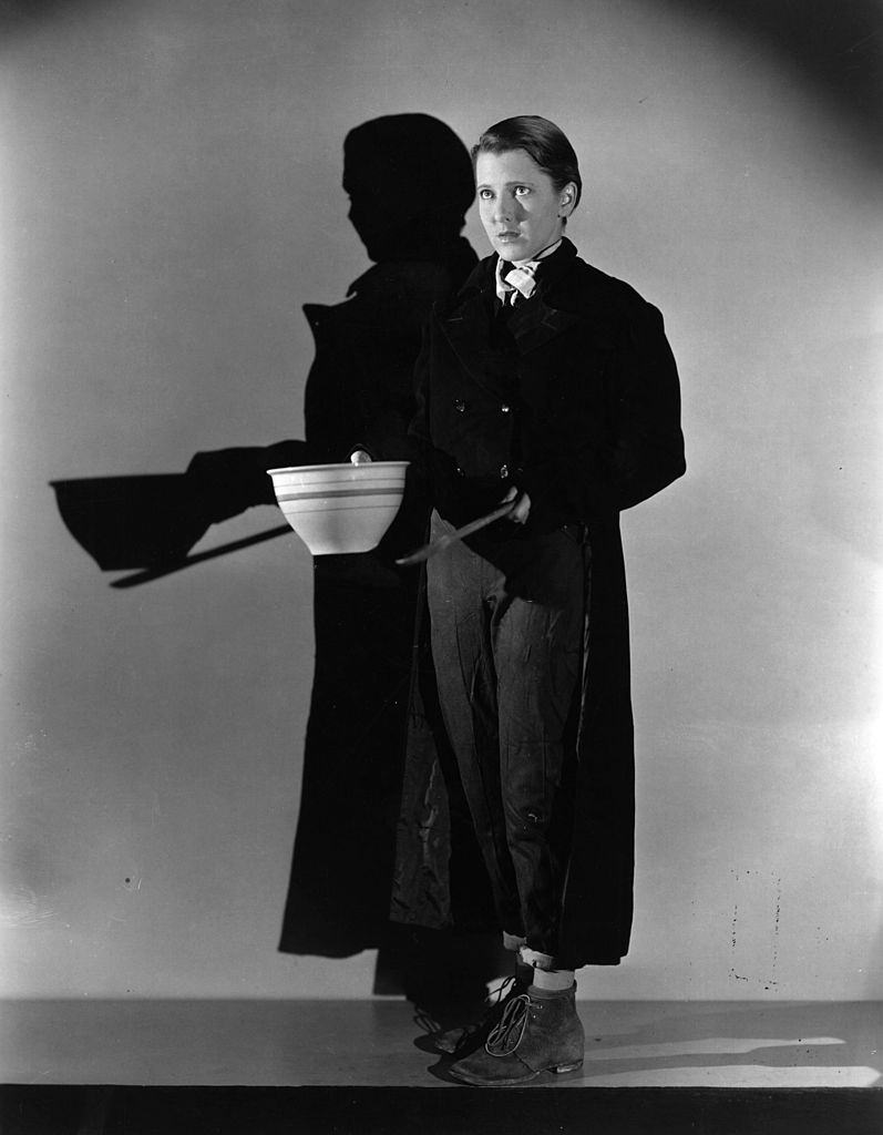 #24 Jean Arthur doing an impression of Oliver Twist, holding out a bowl and asking for more, 1933.