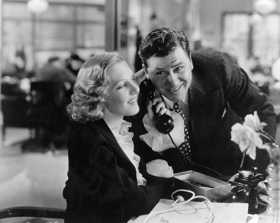 #63 Jean Arthur and Gary Cooper listen to a phone call in a scene from the film ‘Mr. Deeds Goes To Town’, 1936.