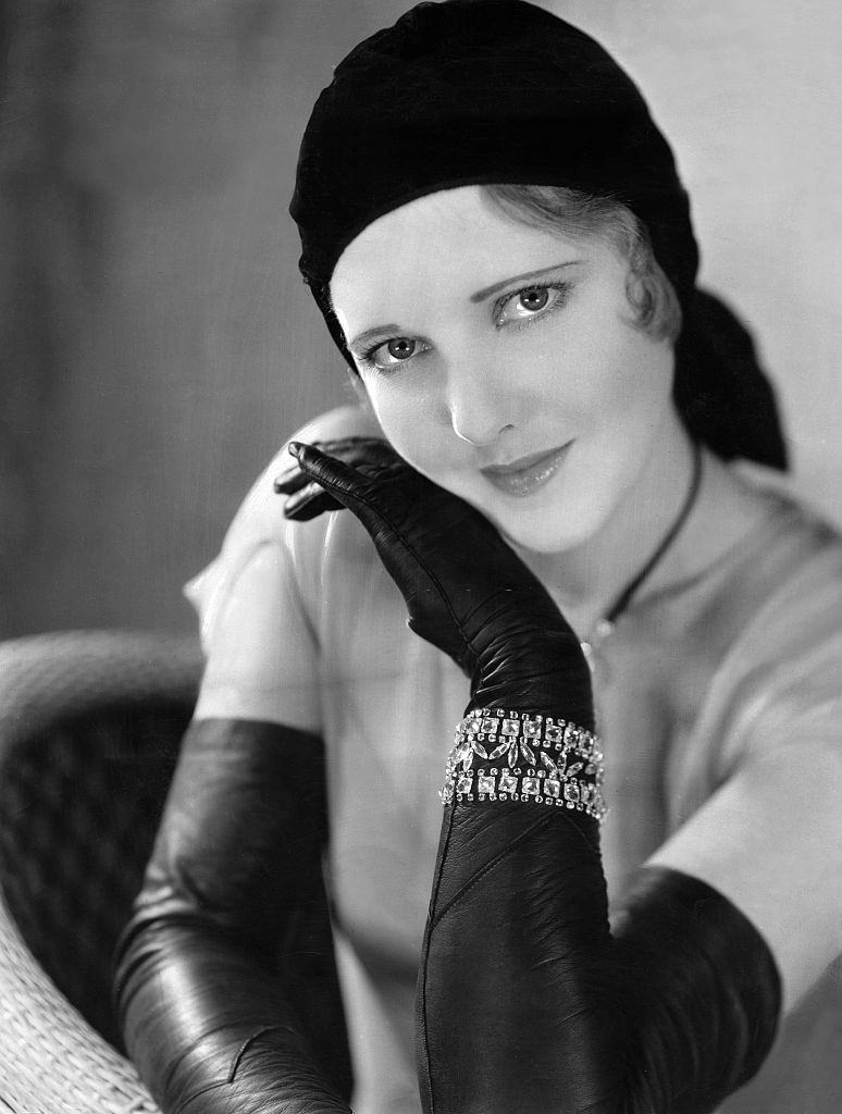 #7 Jean Arthur with hat and long, black leather gloves and arm jewelry, 1930.