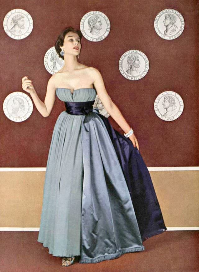 #22 Myrtle Crawford in pale mauve chiffon evening gown, wide satin bands in two tones of purple extend to the floor, by Jacques Fath, 1953