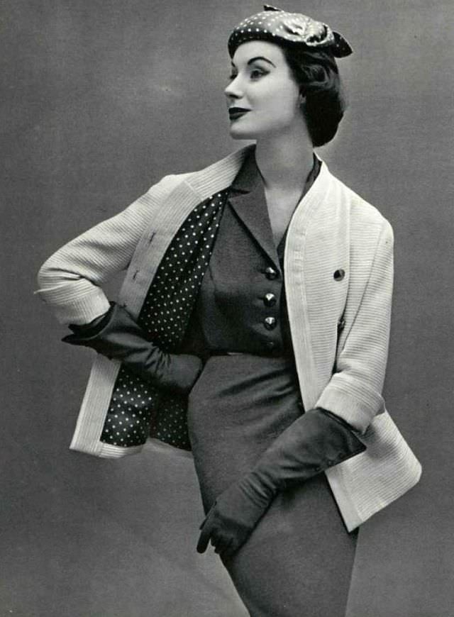 #30 Myrtle Crawford in white ribbed wool jacket worn over gray jersey dress, jacket is lined in gray and white polka-dotted silk, 1953