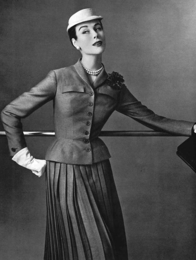 #44 Myrtle Crawford in this short fitted jacket worn over pleated skirt by Jean Patou, 1954.