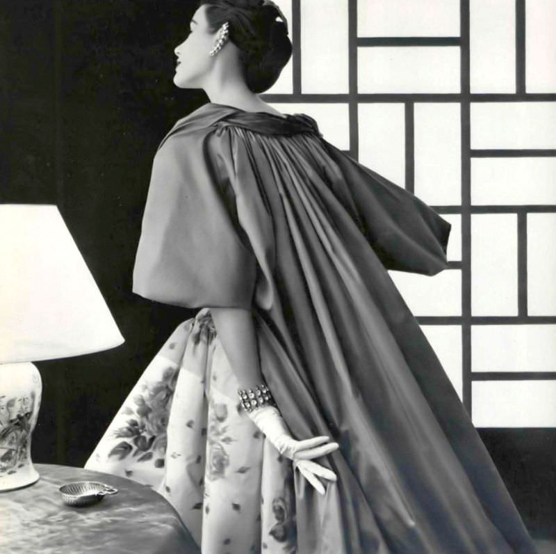 #45 Myrtle Crawford in Venetian style cloak of coral taffeta, worn over white and pink floral print taffeta dress by Jean Patou, 1954.