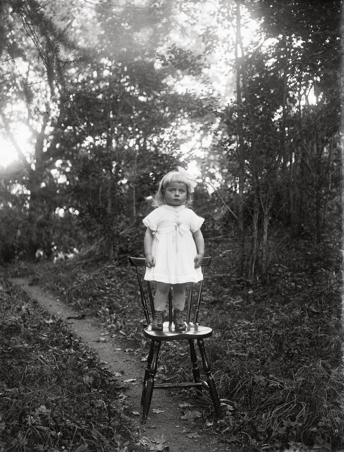 #18 Ljung’s daughter standing by herself on a chair, Torstunaby, Torstuna parish, 1920