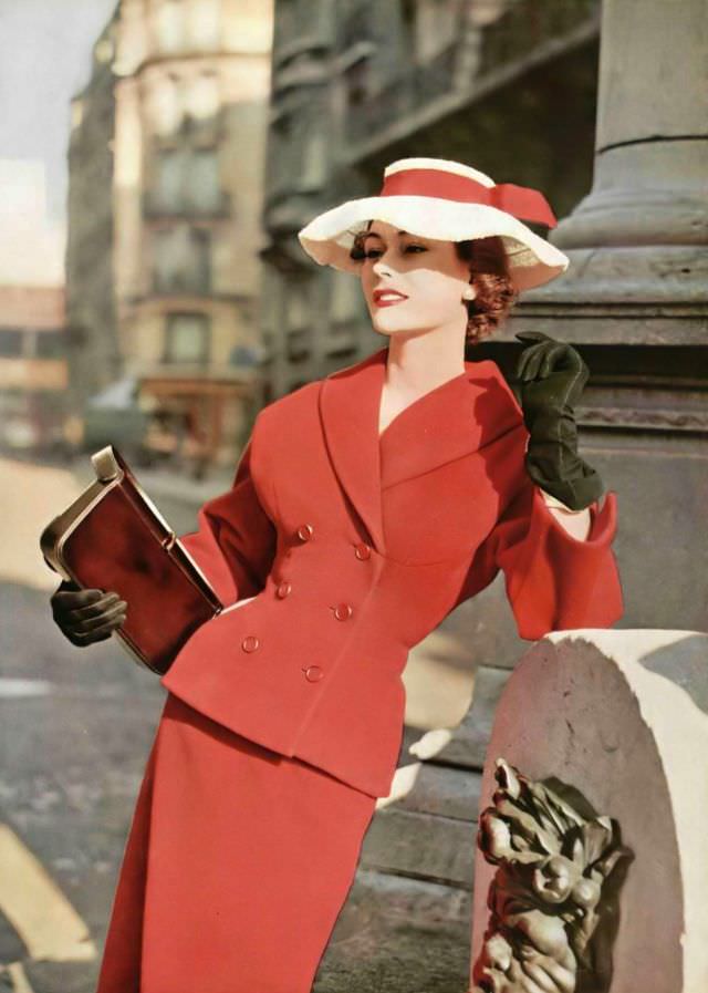 #12 Anne Gunning in poppy red wool suit, double-breasted jacket is fitted with shawl collar and sculpted bustline, by Christian Dior, handbag by Dubost, Paris, 1953