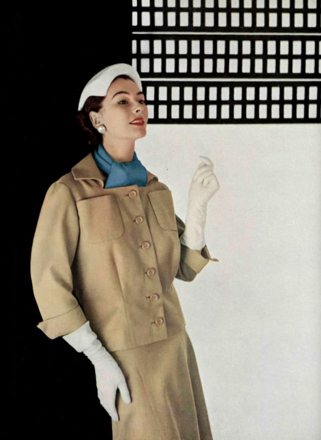 #15 Anne Gunning in tan cotton piqué suit, jacket is boxy with square neckline, bright blue scarf adds color, by Jean Patou, 1953