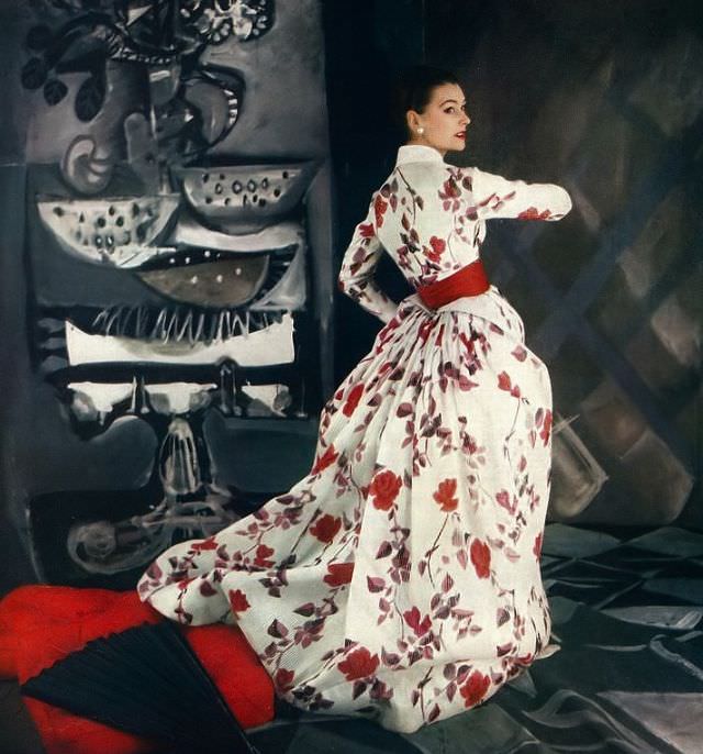 #19 Anne Gunning in beautiful satin-striped silk organdy gown in floral print of reds and dusky leaves worn under its Victorian jacket by Jacques Fath, Vogue, 1954