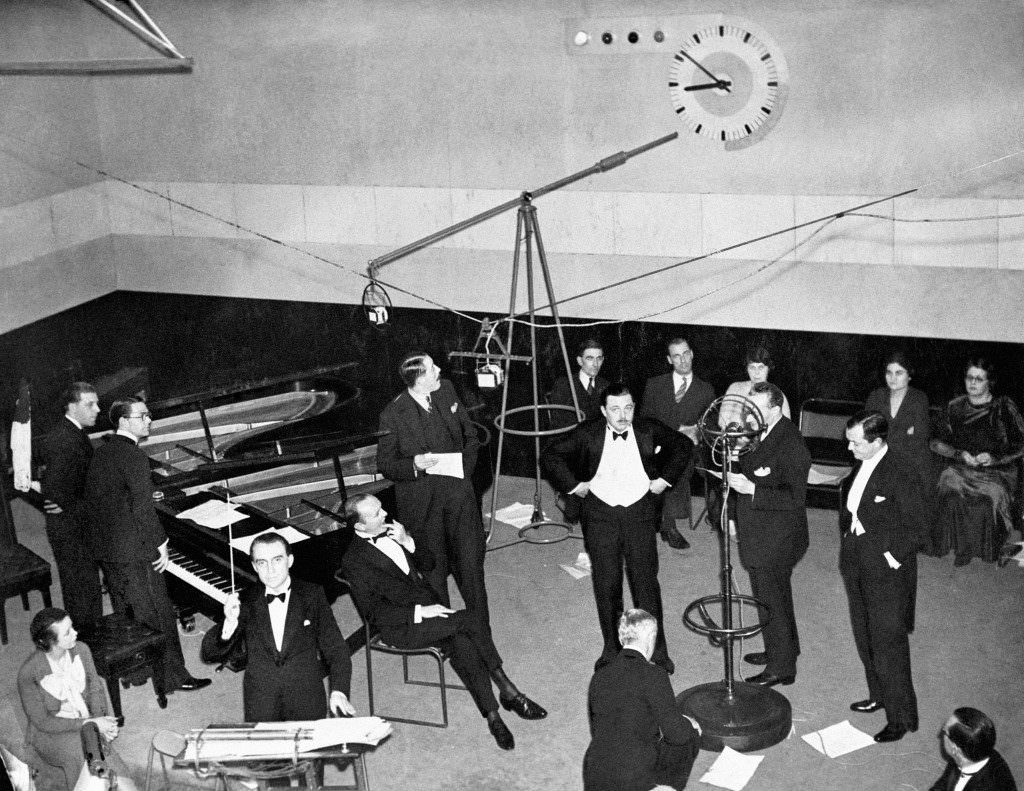#20 1933: A scene in a 1930s BBC recording studio showing Christopher Stone, wearing a dinner jacket, bidding listeners ‘Good Evening’.