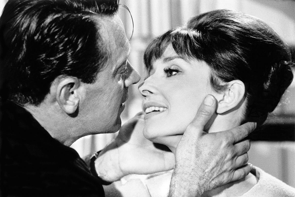 #28 William Holden about to kiss Audrey Hepburn on set of “Paris When It Sizzles” at Boulogne Studios in Paris, 1962