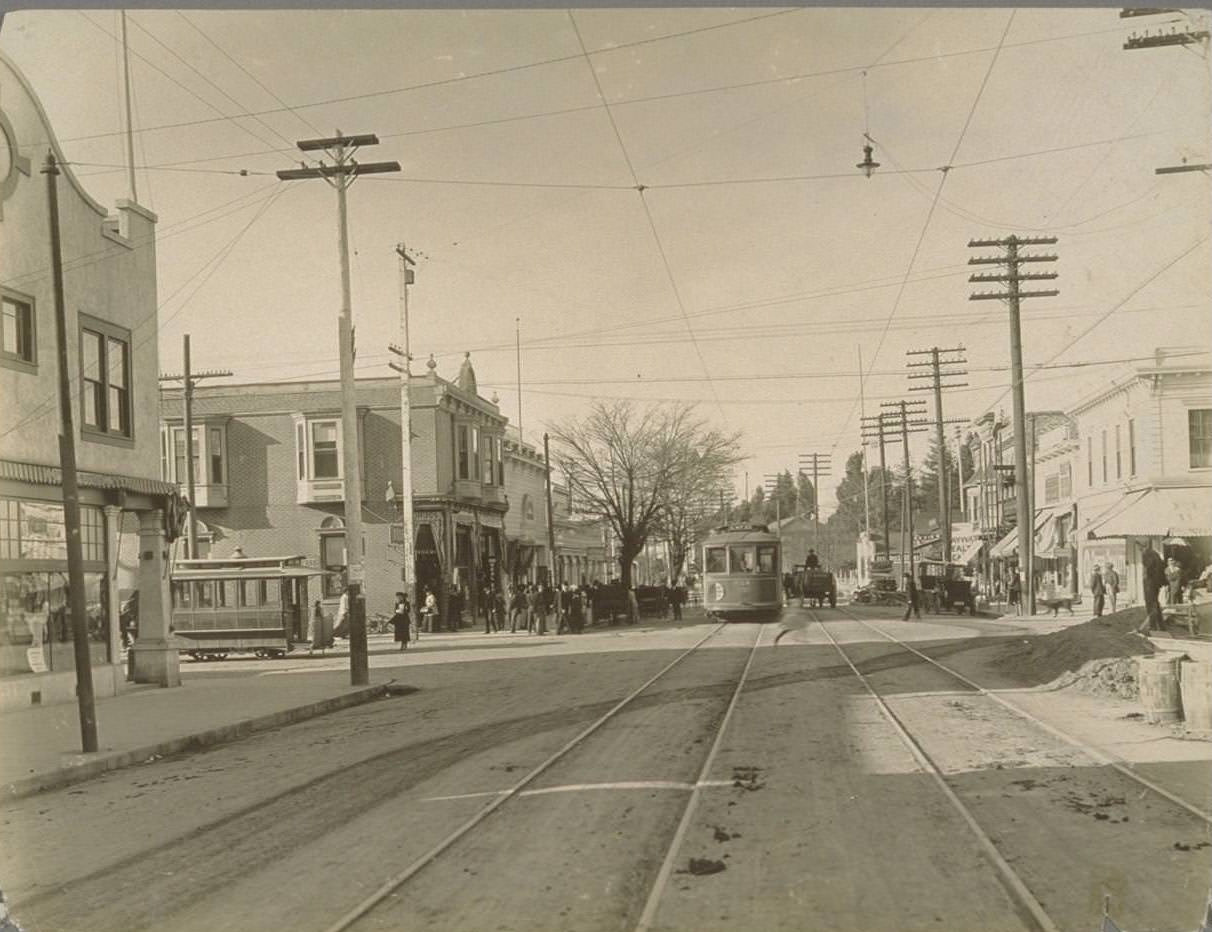#77 Street scene, with electric trolley cars, horse buggies, and automobiles, 1920s.