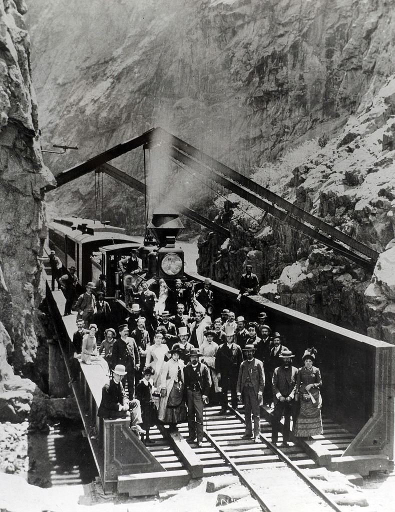 #53 Passengers and crew of the Denver and Rio Grande Western Railway stand by the train as it stops by a cutting cut through the mountains, 1885.