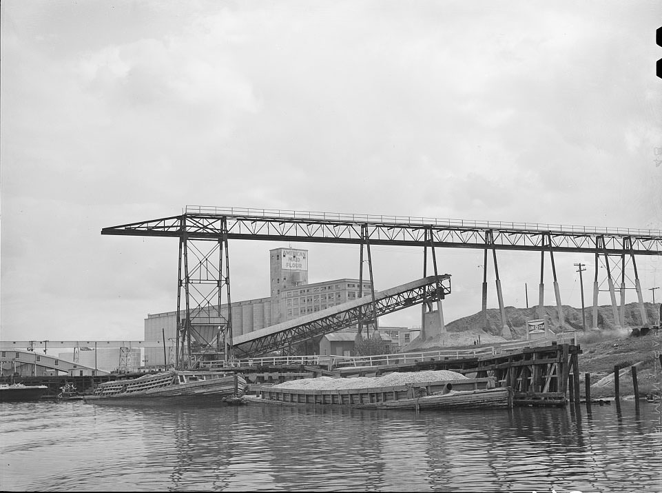 #20 Oyster shell barges at unloading dock of cement plant. Port of Houston, Texas