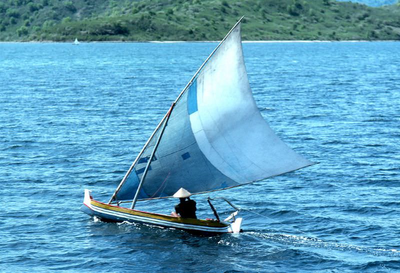 #62 Balinese fisherman in traditional sailing vessel drags a line off the coast of Bali, 1970s
