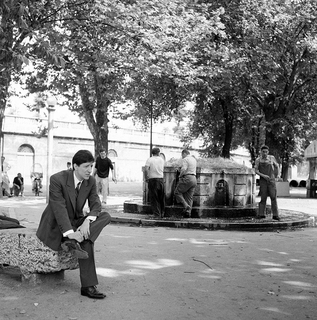 #83 Italian singer-songwriter and actor Giorgio Gaber (Giorgio Gaberscik) sitting in a square. Milan, 1960s.