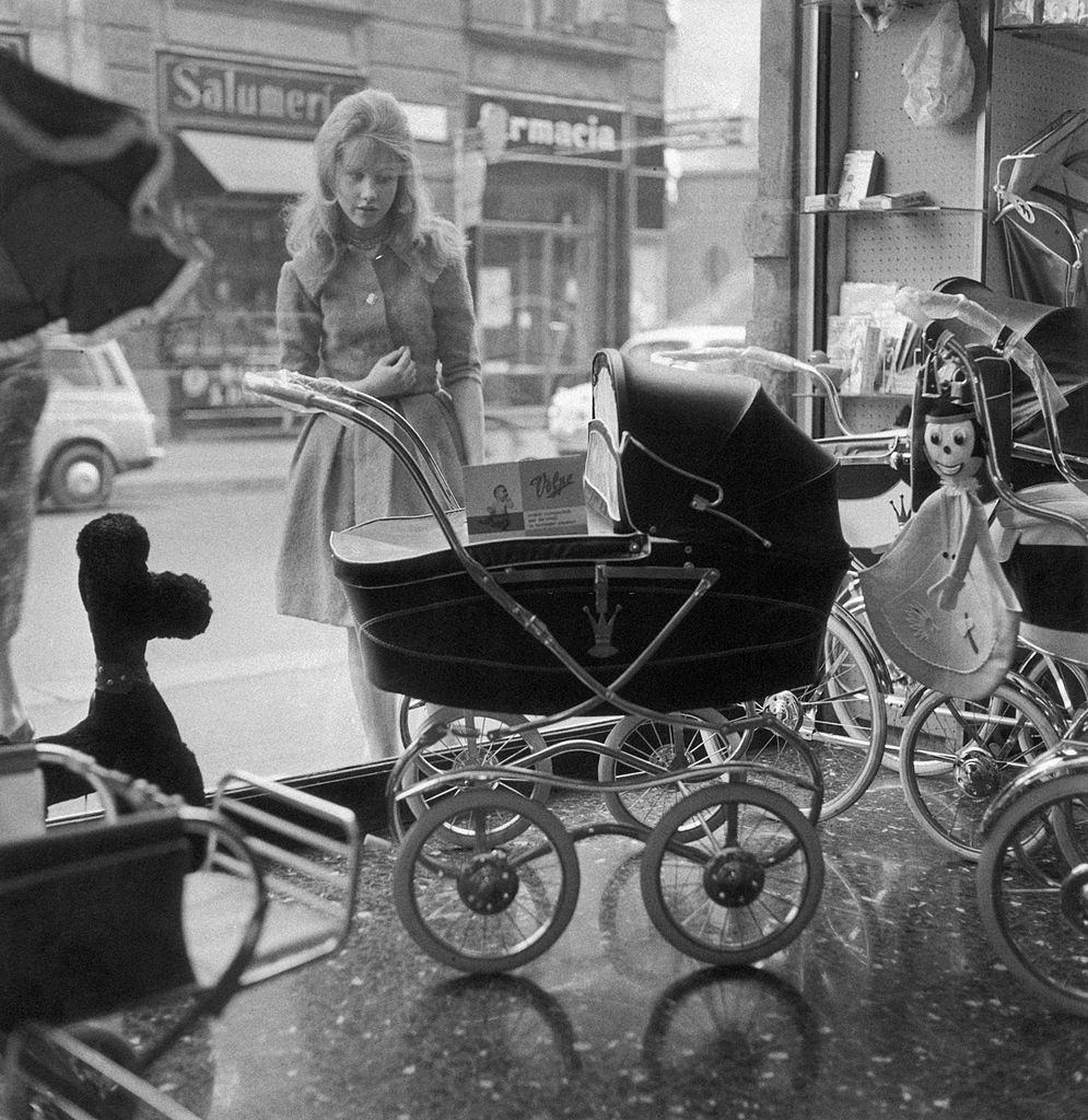 #96 A girl looking at a pram displayed in a shop window, Italy, 1960s.