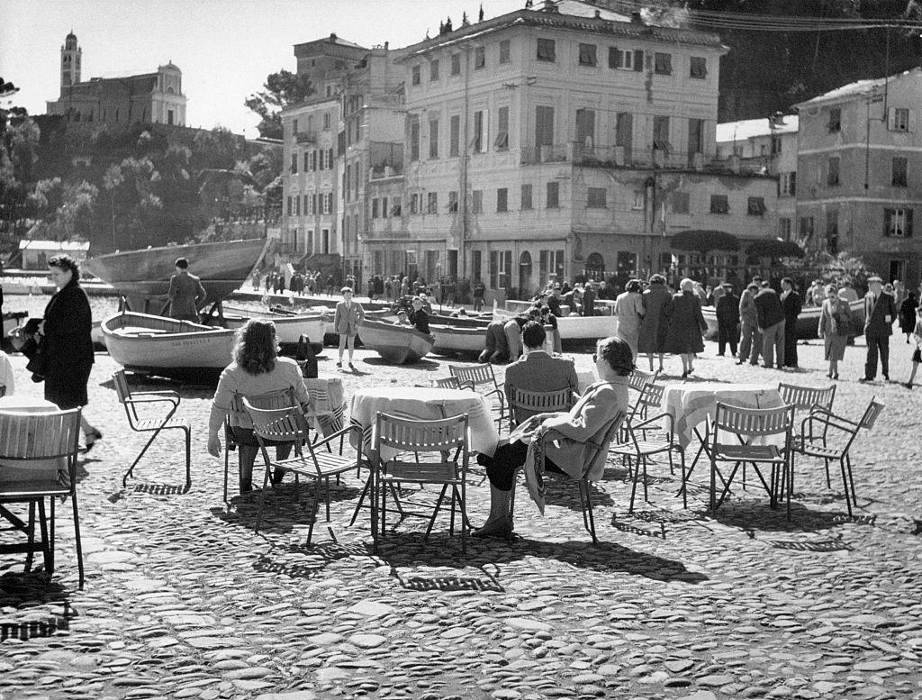 #29 People sitting at the small outdoor tables of a bar in Portofino, 1960s.