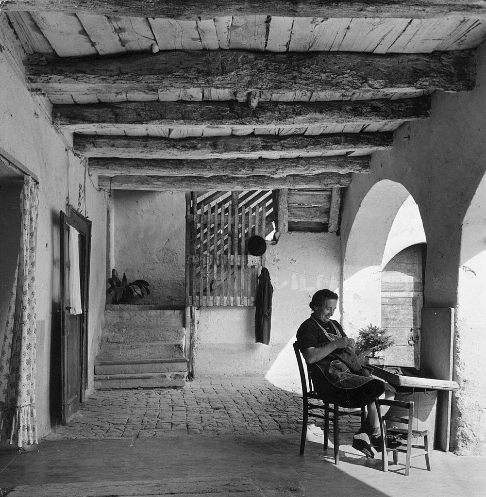 #43 Signora Allessandra Roncalli sits knitting in a covered courtyard, 1960s.