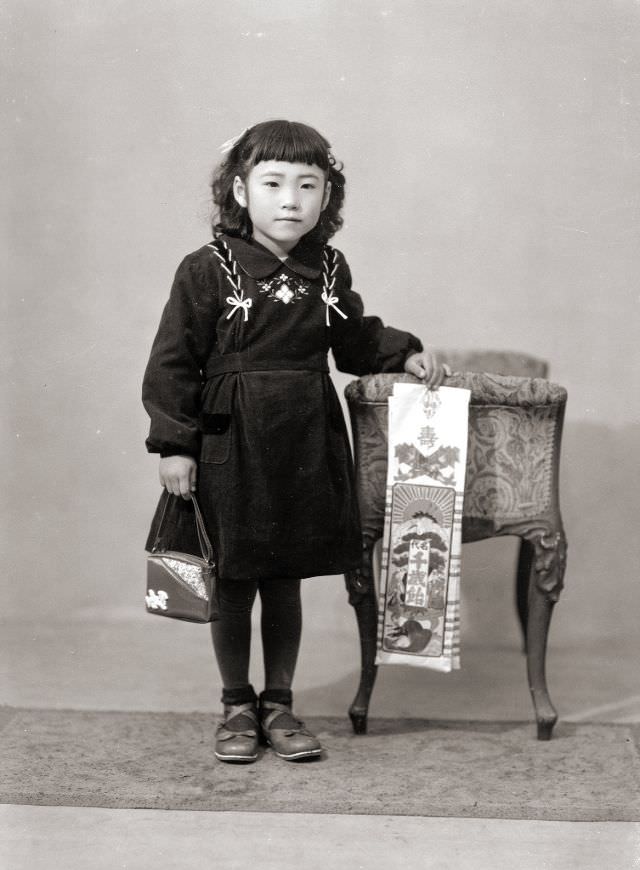 #10 A Japanese girl in a dress, handbag, and flats holding Chitose Ame candy, which is traditional for the Japanese Shichi-Go-San (seven-five-three) holiday