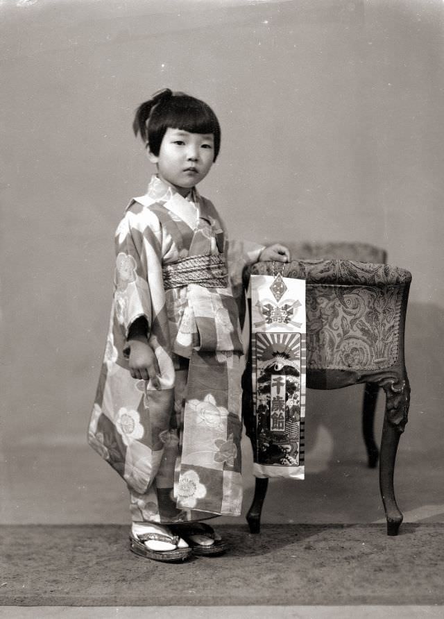 #14 A Japanese girl in a kimono with flowers and checkered pattern. She is also holding Chitose Ame (Thousand Year Candy) for Shichi-Go-San