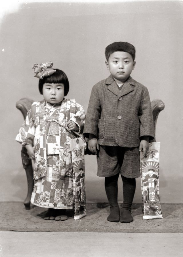 #24 A young Japanese girl in kimono and a young boy in a shorts suit – both of them holding Chitose Ame candy for the Shichi-Go-San Festival