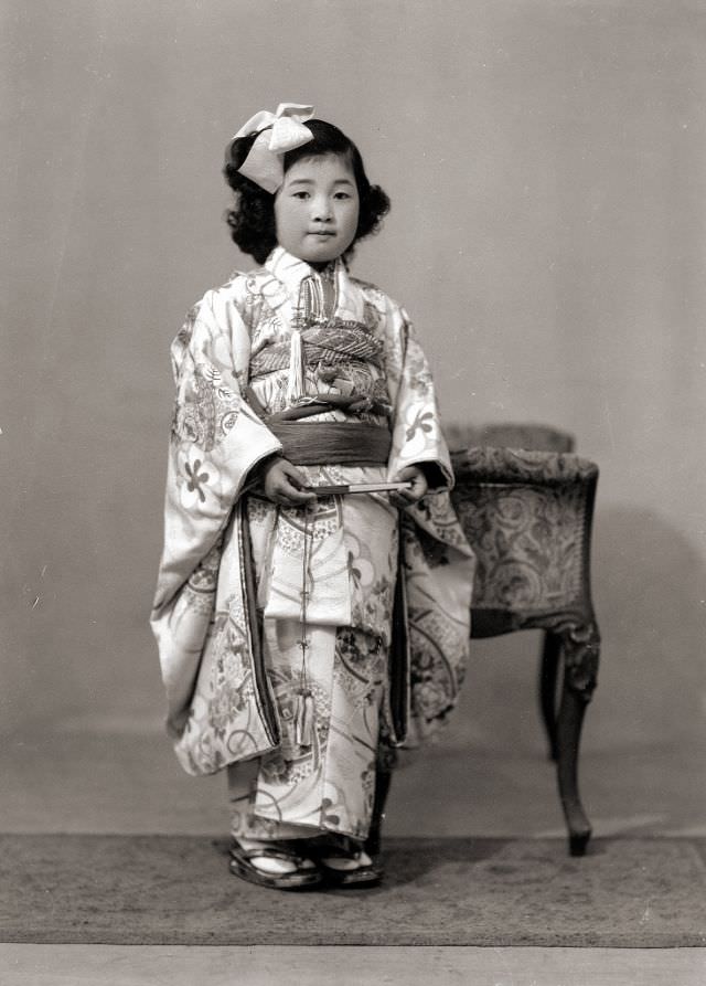 #26 A young Japanese girl in kimono with a hair bow and fan