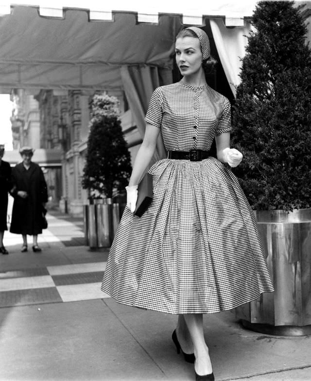 #33 Lillian Marcuson with the outside layers of hat and dress removed, the wide-skirted checked taffeta by Traina-Norell and matching cap by Emme can be worn to parties, 1955