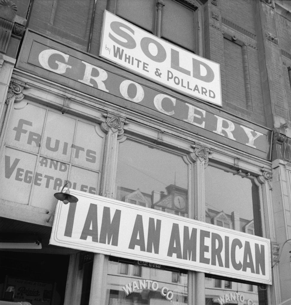 #43 I Am an American’ posted above a grocery store, Oakland, 1942.
