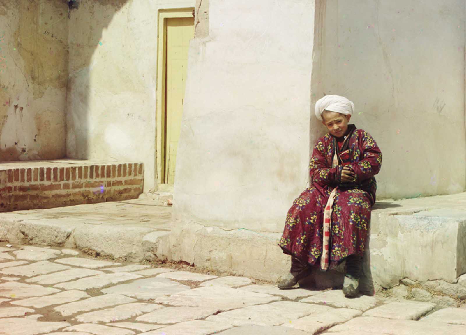 #124 A boy sits in the court of Tillia-Kari mosque in Samarkand, present-day Uzbekistan, 1910.