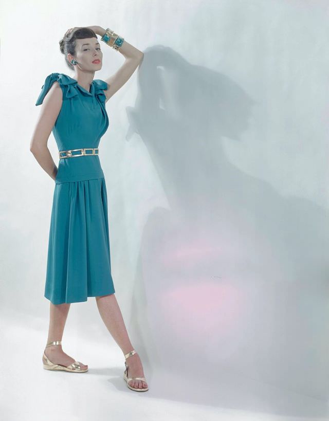 #10 Dorian Leigh in robin’s egg blue dress with bows on top of bare arms, gathered skirt, gold belt by Belt Creations, gold sandals by J & J Slater, jewelry by Hattie Carnegie, Glamour, 1946