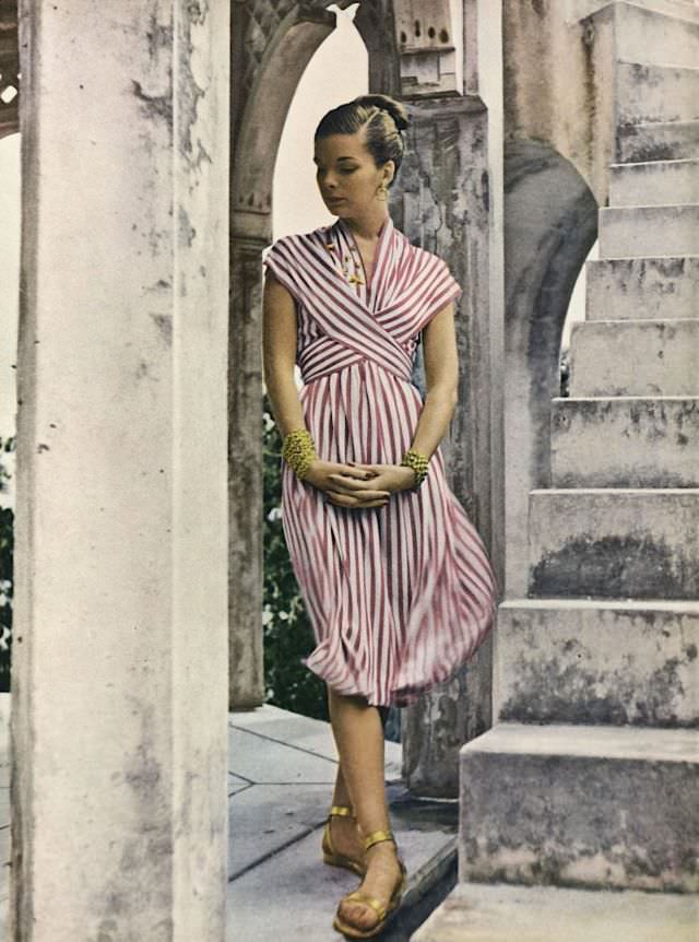 #18 Model is wearing striped rayon jersey dress with wrapped bodice by Mildred Orrick, Vogue, 1946