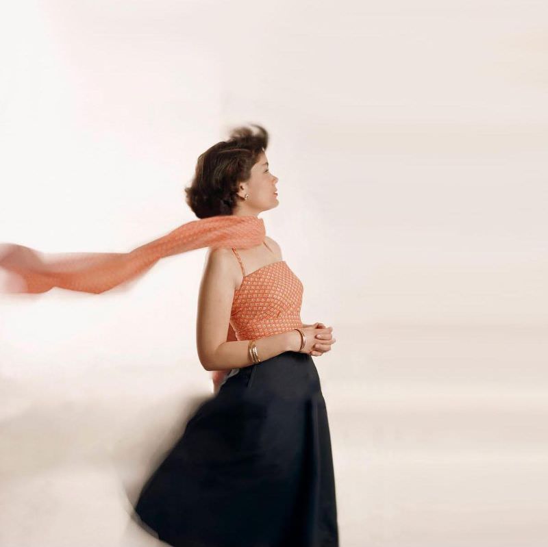 #33 Model kneeling on white background wearing calico top based upon Jr. Vogue Pattern #6453 and black skirt based on Jr. Vogue Pattern # 3165 with cummerbund in calico, Glamour, 1948