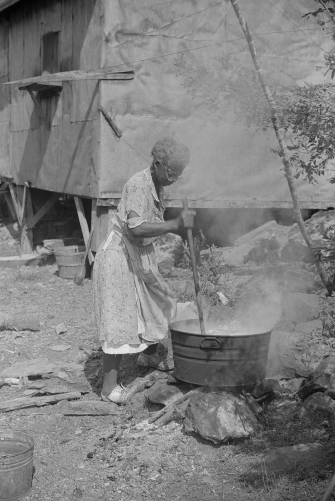 #16 Woman washing clothes outside of shacks along the river, on the highway between Charleston and Gauley Bridge, West Virginia, 1938.