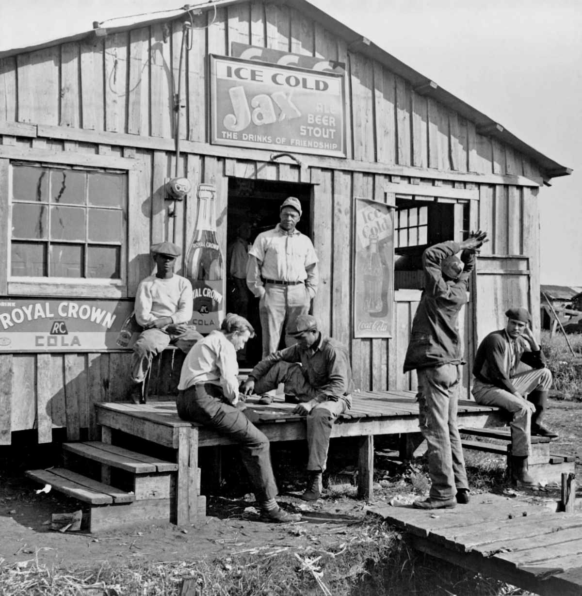 #21 Migratory laborers playing checkers in front of a ‘jook joint’ during slack season for vegetable pickers. Belle Glade, Florida, 1941.