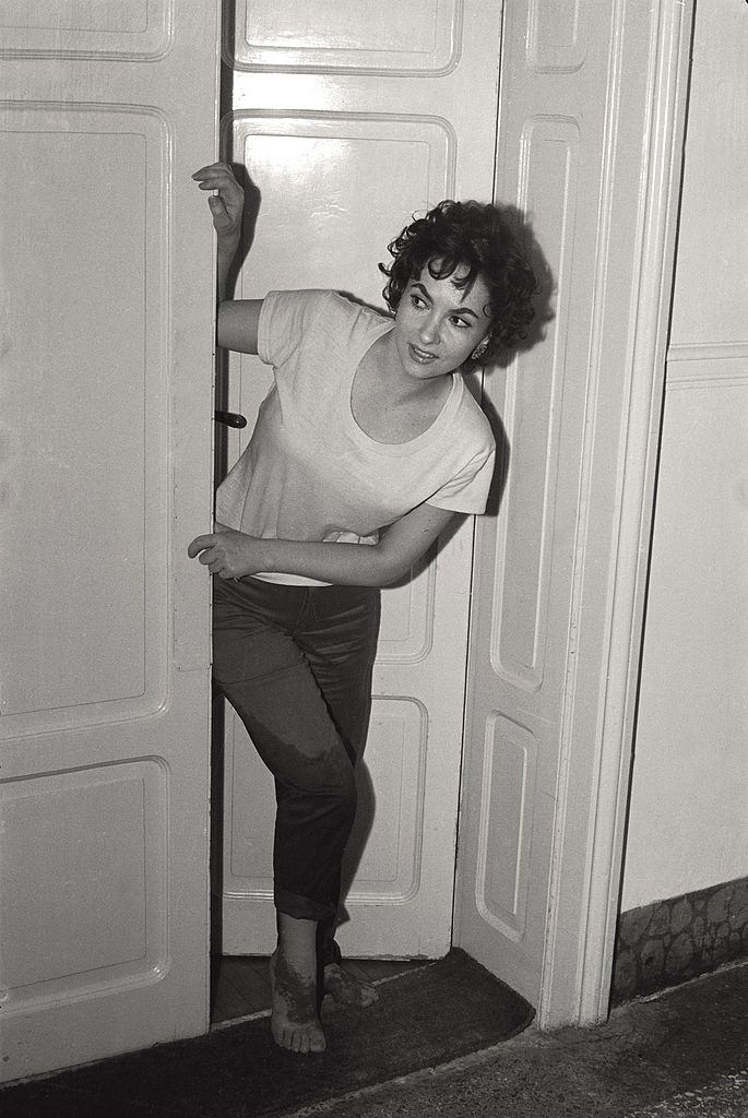 #118 The actress Gina Lollobrigida pokes her head out the door of her hotel room, wet trousers and sanded feet, after going to the beach, during the 17th Venice Intenational Film Festival.