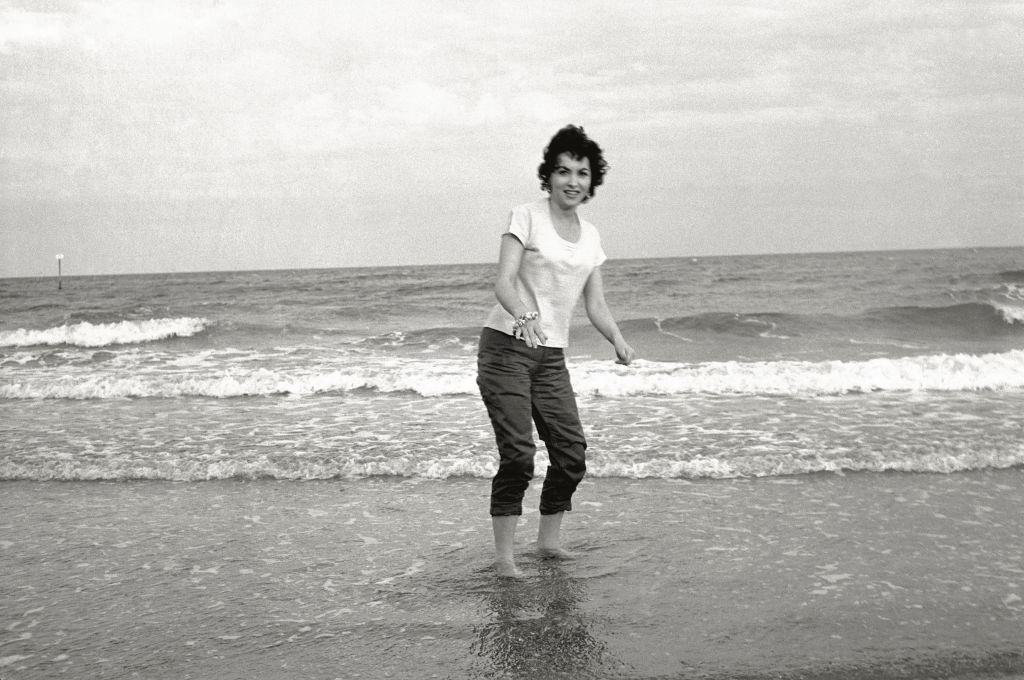 The actress Gina Lollobrigida on the seashore, her feet in the water, during the 17th Venice Intenational Film Festival. Venice (Italy), 1956.