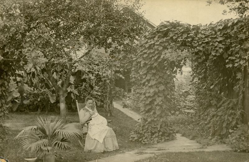 #15 Katherine Horack, sitting in a rocking chair in her garden, creating a drawn work tablecloth for her daughter, Bertha, 1895-1897