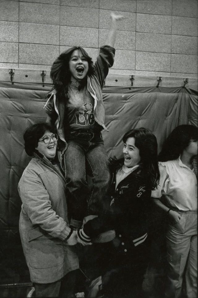 #3 Two teenage girls hold up a third cheering teenage girl