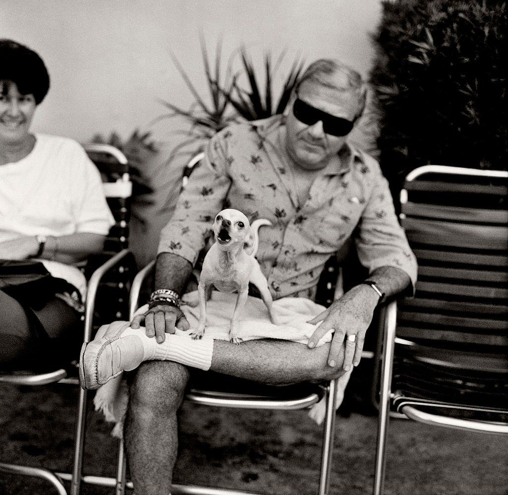 #65 Man with angry dog sitting on hotel veranda on Collins Avenue, Miami Beach, Florida.