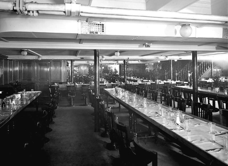 The forward section of Aquitania’s 3rd Class Dining Saloon, on the Lower Deck (F Deck), looking across to the port side. Stairs up to the Main Deck are visible in the background on the right, May 1914