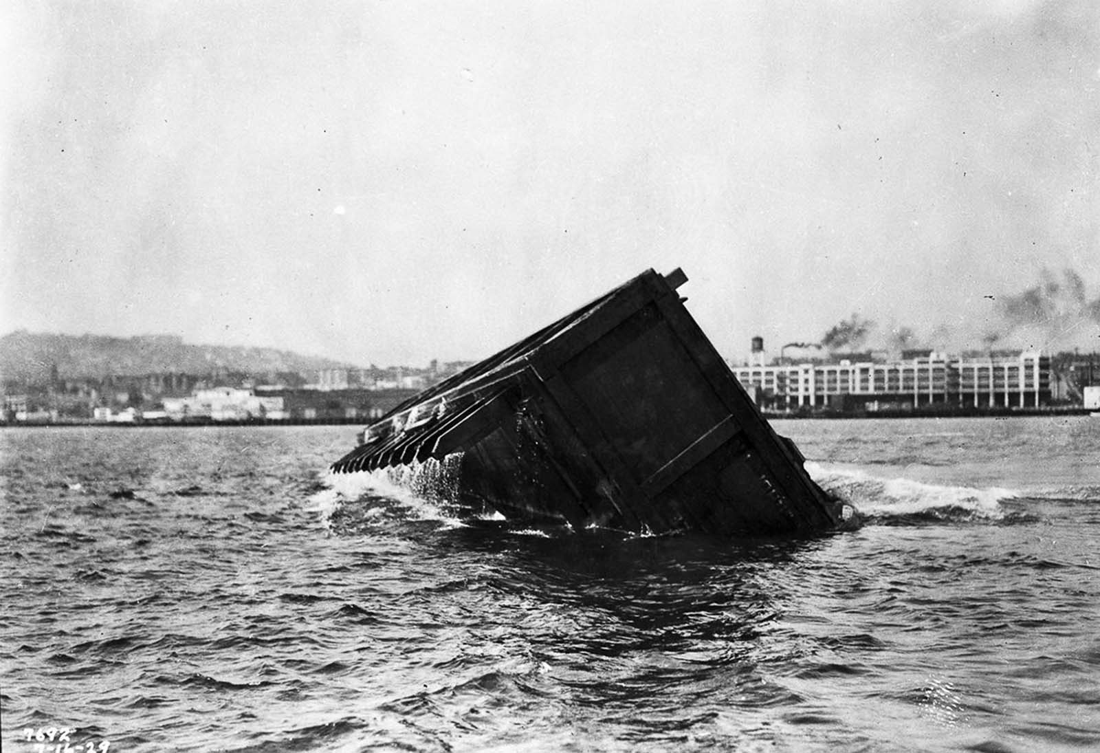 #25 A self-capsizing scow carrying earth dumps its load into the city’s harbor.