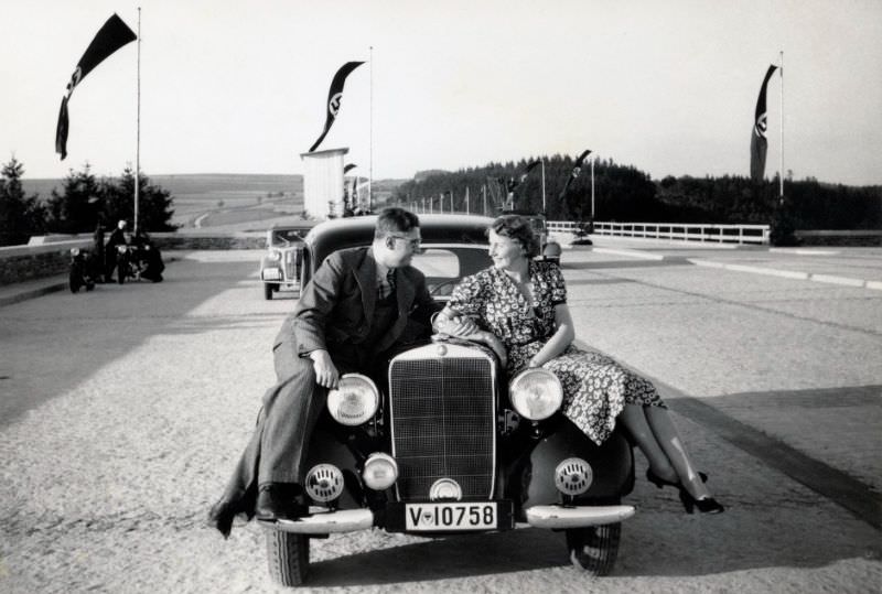 #37 A fellow in a pinstripe suit and a lady in a floral dress posing on the fenders of a Mercedes-Benz 170 V, near the town of Plauen in Saxony.