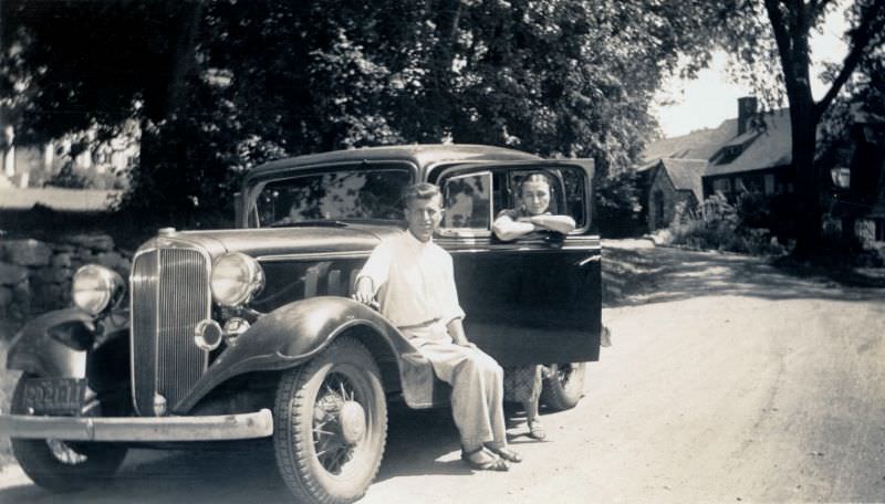 #26 A leisurely clad couple posing with a 1933 Chevrolet Sedan on a sunny summer’s day.