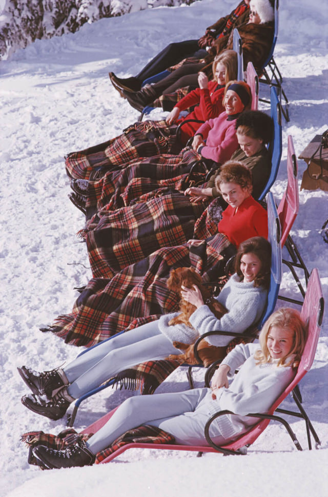 #10 A group of women reclining on the snow in Gstaad with rugs covering their knees, 1963.