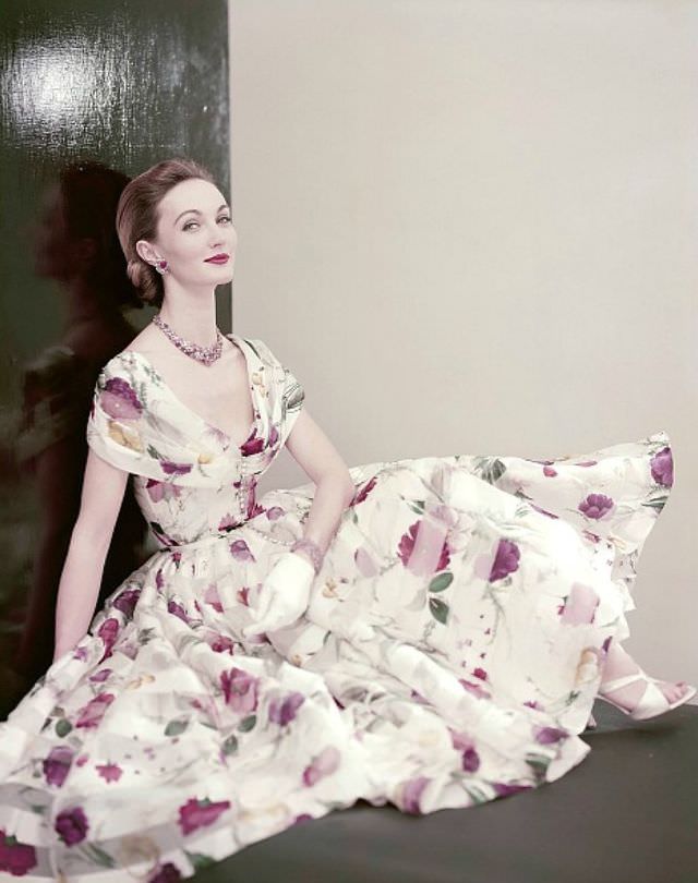 Evelyn Tripp wearing a dress of floral printed white silk organdy with a beaded necklace and bracelet of tourmalines and diamonds, 1955