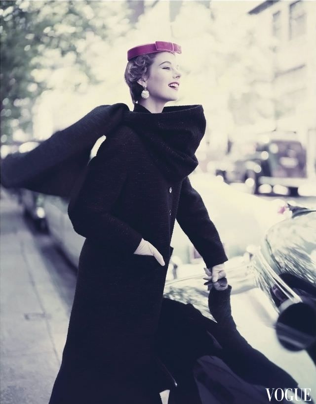 #9 Model wearing narrow long wool woven black coat with a stole and tambourine hat, 1953